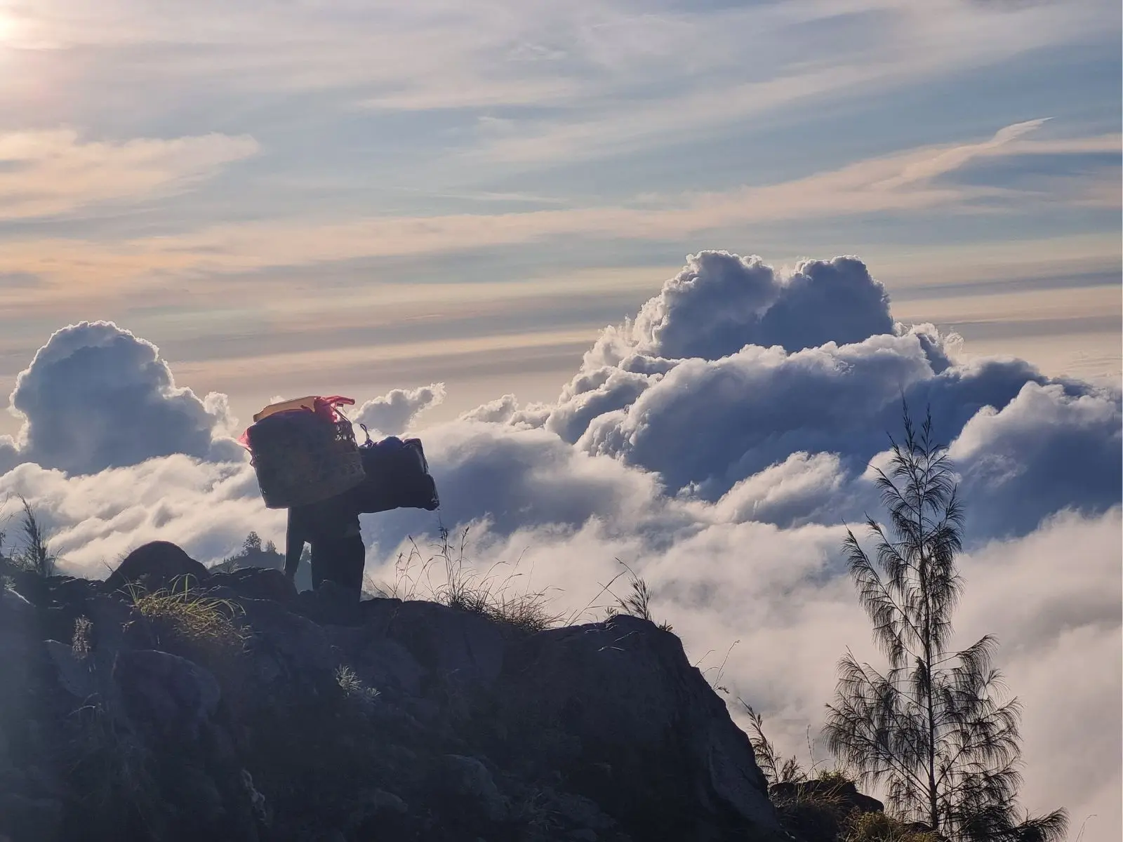 Mount Rinjani porter carrying equipment along a steep ridgeline